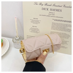 Close-up of beige quilted cylinder bag with gold chain strap and large pearl detail