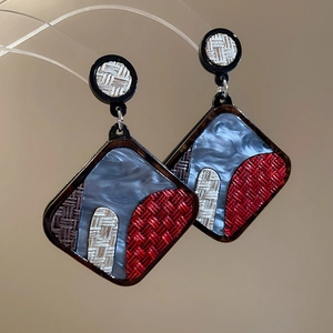 Macro shot of geometric acrylic earrings with marble texture and woven resin pattern