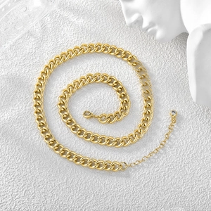 18K gold plated Cuban link necklace with sparkling zircons on a textured white surface