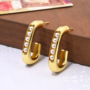 Minimalist gold-plated C-shaped earrings with six white pearls in a professional macro view