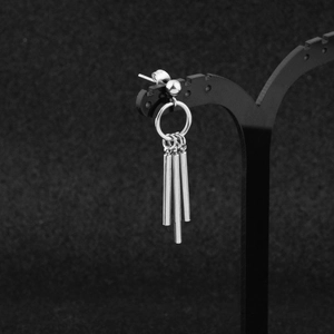 Detail of silver stainless steel drop earrings with hanging cylindrical pendants