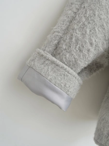 Detail der grauen Plüschjacke mit weicher Textur und Innenfutter aus Satin am Ärmel