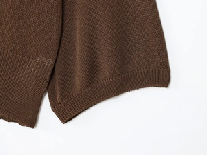 Detail of dark brown fine knit sweater featuring elastic ribbed cuff and premium texture