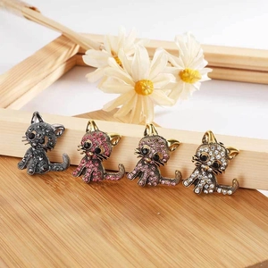 Detailed view of rhinestone cat brooches in black, pink, purple, and white colors