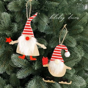 Wooden Christmas gnome ornaments with red hats hanging on a green pine tree branch