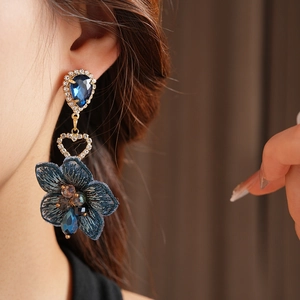 Détail de boucle d'oreille vintage fleur en tissu bleu marine avec cristaux et strass dorés