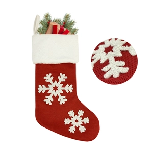 Detail of red knitted Christmas stocking with plush white cuff and 3D snowflake texture