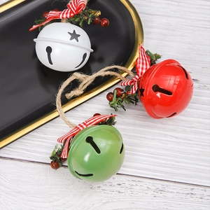 Close-up of red, white and green Christmas bells with bows and berries on a wood background