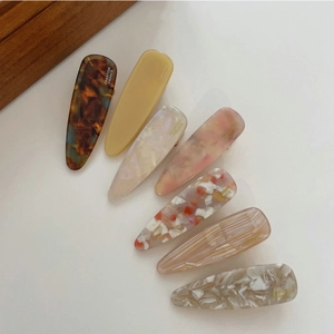 Detailed close-up of a 7-piece set of acetate hair clips with marble and floral patterns