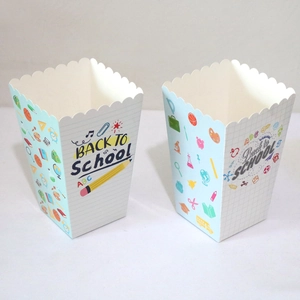Macro shot of two paper popcorn boxes with Back to School stationery patterns and wavy edges