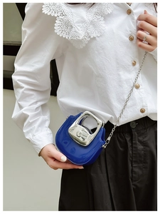 Close-up of stylish mini blue handbag with silver chain strap and metal handle detail