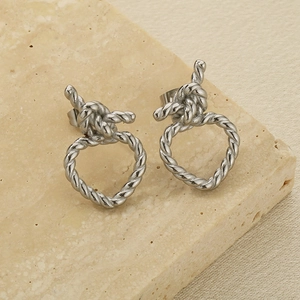 Détail macro de boucles d'oreilles nœuds torsadés argentés sur une pierre beige