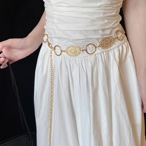Vintage golden metal waist chain with oval textured links on a white dress