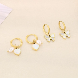 Gold hoop earrings with heart white shell, pearl, and butterfly pendants on beige fabric
