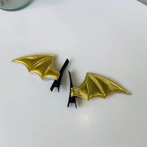 Close-up of golden bat wing hair clips with black metal alligator clips for Halloween