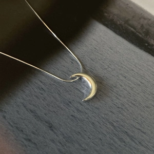 Minimalist 925 sterling silver crescent moon necklace on textured grey background