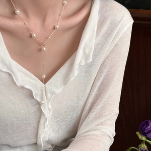 Detail of elegant pearl necklace with gold chain and dangling fringe on a female model