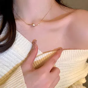 Close-up of elegant gold pearl pendant necklace on collarbone with cozy sweater background