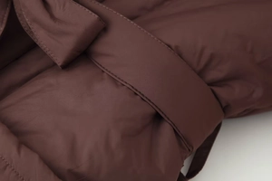 Close-up of dark brown padded jacket fabric texture and adjustable waist belt detail