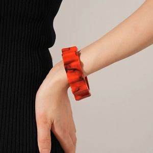 Detail of red and black marble resin cuff bracelet with unique wavy edges on model