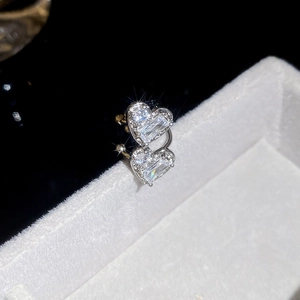Gros plan d'une manchette d'oreille double cœur avec zircons sur velours blanc