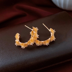 Gros plan sur les boucles d'oreilles dorées en C avec zircon et texture rétro riche