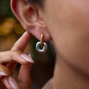 Gros plan de boucles d'oreilles géométriques bicolores en acier inoxydable sur modèle