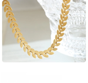 Macro shot of 18K gold leaf-shaped link necklace with a brushed metal texture finish