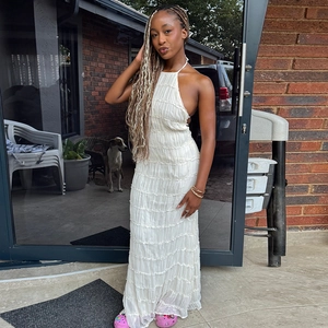 Outdoor full shot of a white halter neck pleated dress with an elegant backless design
