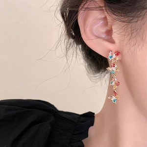 Close-up of dangling long earrings featuring colorful zircon butterflies on a model