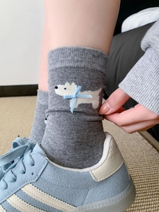 Dettaglio di calza in cotone grigio con motivo a cane e fiocco blu con scarpe da ginnastica