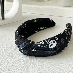 Détail d'un serre-tête d'Halloween à nœud avec motifs tête de mort, toile d'araignée et yeux