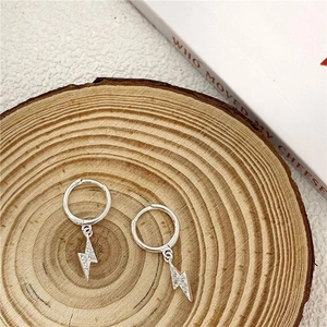 Detail of silver lightning bolt earrings with pavé crystals on a rustic wooden background