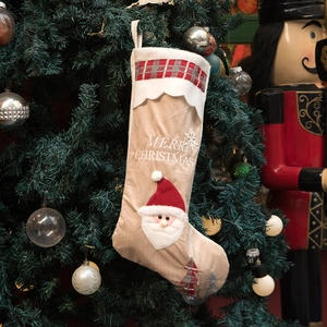 Classic plaid Christmas stocking hanging on a tree with Santa Claus and Merry Christmas text