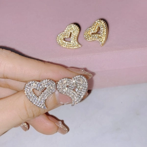Elegant gold and silver heart stud earrings with full cubic zirconia stones on model hand