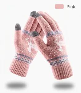 Close-up of pink winter knit gloves with reindeer pattern and gray touchscreen fingertips