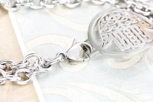 Detailed macro view of the silver double-layered chain bracelet and its lobster clasp