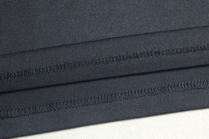 Detailed close-up of double-needle stitching on the hem of a black knit bodycon dress