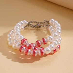 Détail d'un bracelet triple rang de perles blanches avec accents rouges et fermoir argent