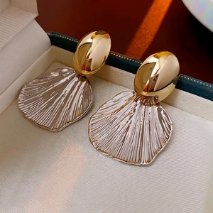 Two-tone gold and silver shell earrings with textured metallic finish in a jewelry box