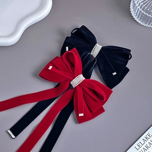 Detail of red and black velvet bow hair clips featuring sparkling rhinestone tassels