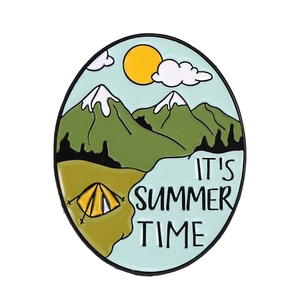 Detail of enamel pin featuring a mountain landscape and IT'S SUMMER TIME text on white background