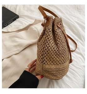 Close-up of woven texture on khaki straw bucket bag with brown leather drawstring closure