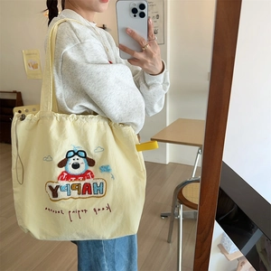 Detail of yellow canvas tote bag featuring cute dog embroidery and drawstring closure