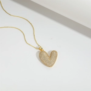 Elegant gold heart pendant necklace with shimmering white zircons on a white background