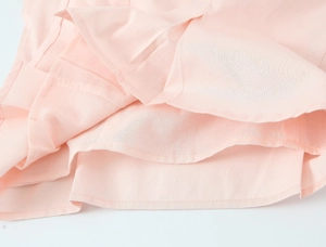 Detail shot of light pink flutter sleeves with professional stitching on woven fabric