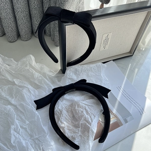Close-up of two black velvet bow headbands with handmade labels on textured background