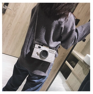 Silver sequin camera-shaped crossbody bag with chain strap shown on a model's shoulder