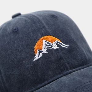 Macro shot of embroidered sunrise and mountain peak on washed cotton baseball cap