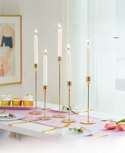 Set of five gold European iron candlesticks in various heights on a decorated dining table